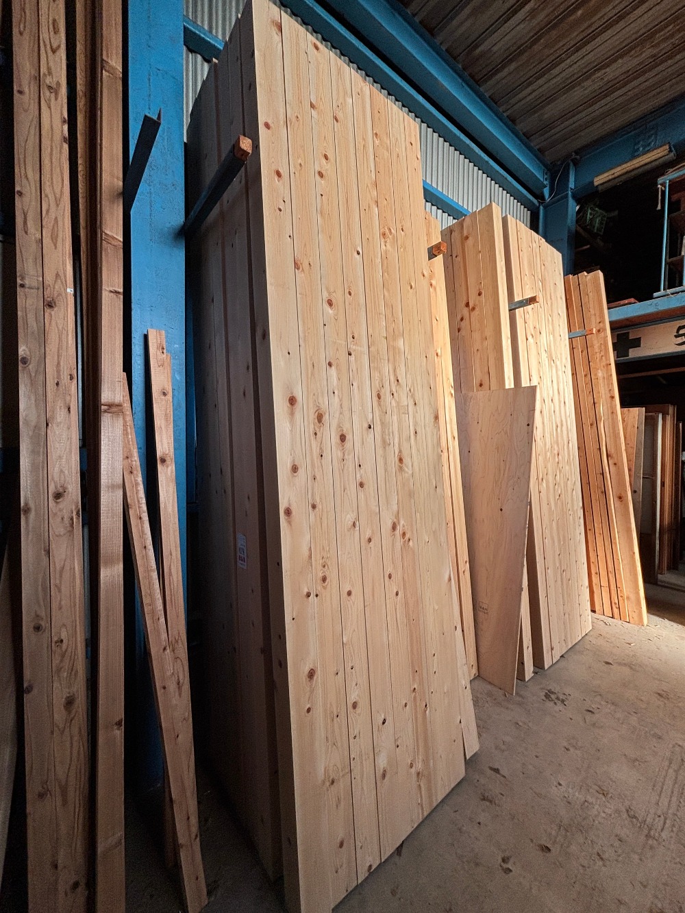 先日搬入した東濃桧の柱材を背景に、 エステックウッドのデッキ材へ塗装作業を行っています。 