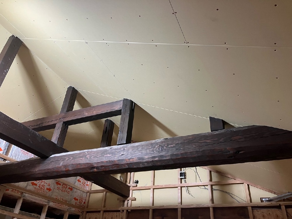勾配天井のボード貼り作業を進めています。立派な梁が際立っています。（山本）