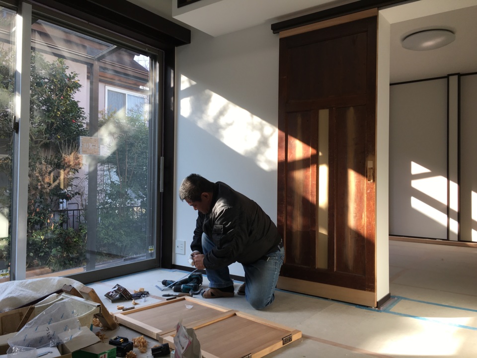 再生した古い建具の前で、仕事をする長瀬さん。