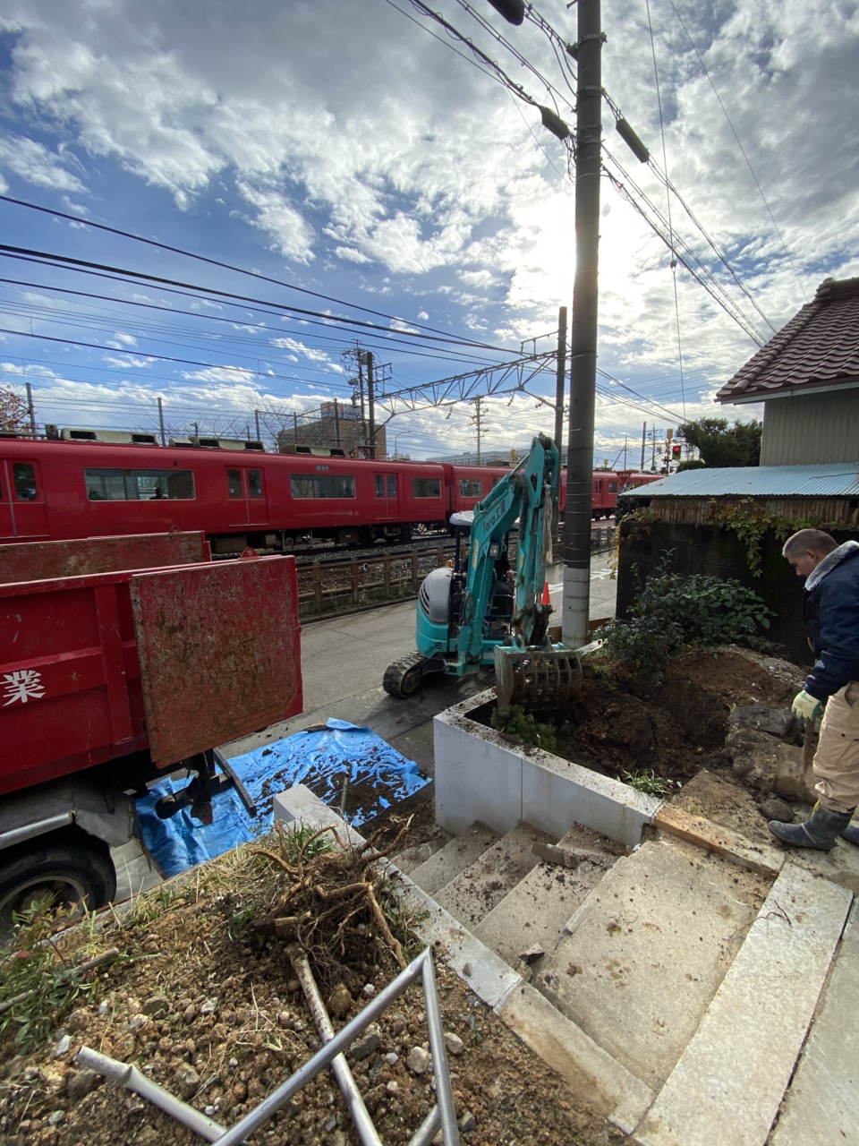 今日から外構工事着工です 車庫の土を掘削していきます 後ろに名鉄電車が通っていきます（山本）